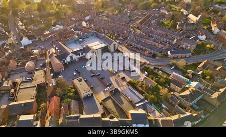 Vista aerea della città con supermercato, parcheggio, case e chiesa. La calda illuminazione del sole mette in risalto la scena a Ripon, Regno Unito. Foto Stock