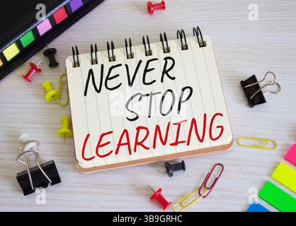 Non smettere mai di imparare il simbolo. Le parole concettuali non smettono mai di imparare su un notebook di legno. Bellissimo sfondo in legno. Business e non smettere mai di imparare Foto Stock