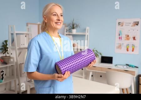 Fisioterapista femminile con rullo in gommapiuma nel centro di riabilitazione Foto Stock