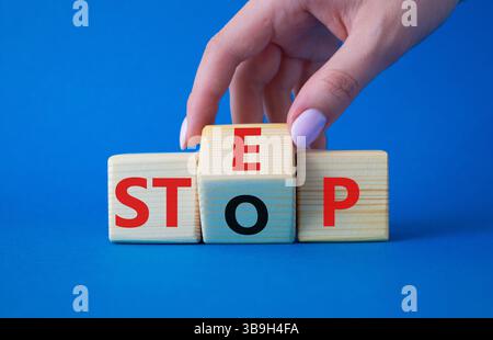 Simbolo passo vs arresto. L'uomo d'affari trasforma i cubi di legno e cambia la parola Stop to Step. Bellissimo sfondo blu. Step vs Stop e business Conce Foto Stock