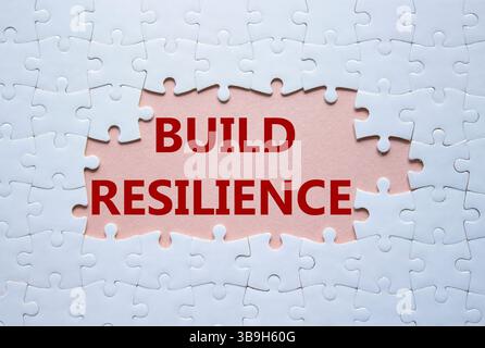 Simbolo di resilienza. Puzzle bianco con parole per una maggiore resilienza. Bellissimo sfondo rosa. Business e creazione di un concetto di resilienza. Copia spazio. Foto Stock