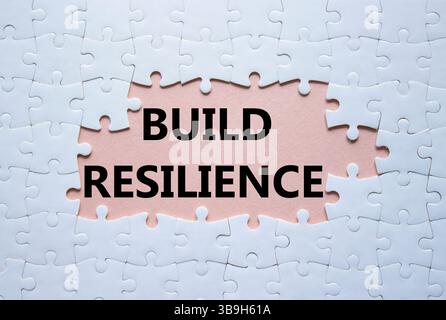 Simbolo di resilienza. Puzzle bianco con parole per una maggiore resilienza. Bellissimo sfondo rosa. Business e creazione di un concetto di resilienza. Copia spazio. Foto Stock