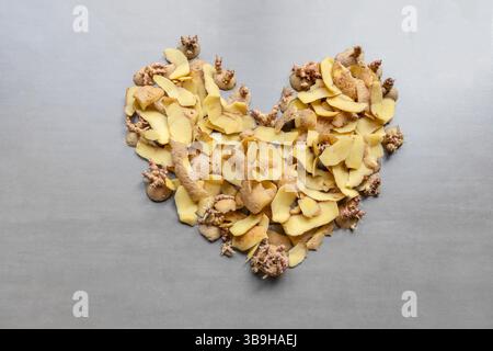 I frammenti di patate e le pelature si trovano a forma di cuore su sfondo grigio sul tema dei rifiuti organici e della separazione organica Foto Stock