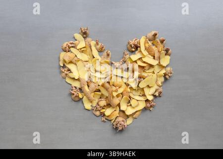 I frammenti di patate e le pelature si trovano a forma di cuore su sfondo grigio sul tema dei rifiuti organici e della separazione organica Foto Stock