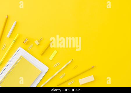 Concetto di ritorno a scuola, forniture scolastiche e accessori su sfondo giallo, notebook, matite, graffette, polvere, spazio di copia con disposizione piatta Foto Stock