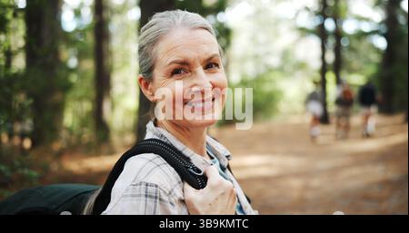 Escursioni, foresta e ritratto di donna matura in natura con zaino per l'esercizio fisico, la camminata e la salute. Fitness, viaggi e persona nei boschi per il trekking Foto Stock