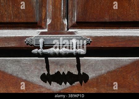 Primo piano della maniglia vintage in metallo su una vecchia porta in legno con ombra Foto Stock
