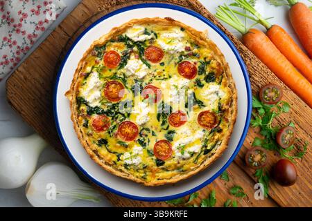 Quiche francese con spinaci, formaggio, pomodori e prosciutto a dadini. Tavolo con vista dall'alto e decorazioni natalizie. Foto Stock