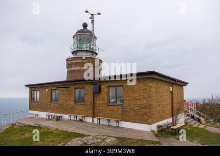 Vecchio faro in piedi su una scogliera rocciosa vicino al mare a Kullen, Svezia. Giorno primaverile coperto dalla costa. Foto Stock