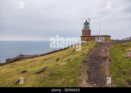 Vecchio faro in piedi su una scogliera rocciosa vicino al mare a Kullen, Svezia. Giorno primaverile coperto dalla costa. Foto Stock