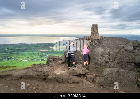 Una madre e una figlia godono di una vista mozzafiato dalla cima di una maestosa montagna Slieve Foye, ammirando gli splendidi paesaggi lussureggianti e il Foto Stock
