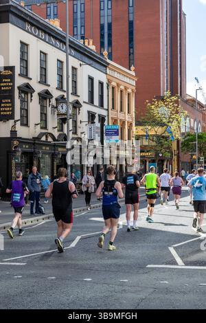 I corridori della maratona di Belfast corrono davanti al famoso Crown Bar di Belfast. Foto Stock