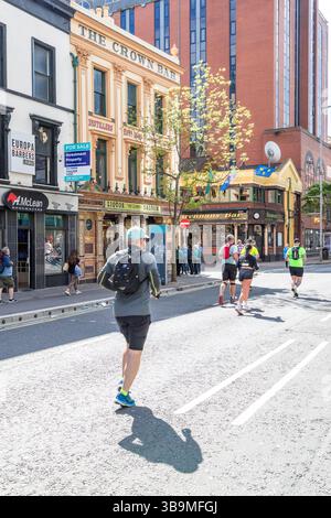 I corridori della maratona di Belfast corrono davanti al famoso Crown Bar di Belfast. Foto Stock