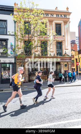 I corridori della maratona di Belfast corrono davanti al famoso Crown Bar di Belfast. Foto Stock