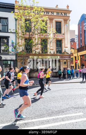 I corridori della maratona di Belfast corrono davanti al famoso Crown Bar di Belfast. Foto Stock