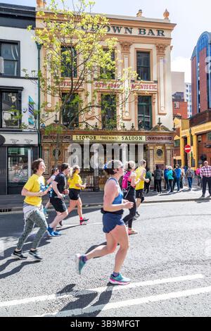I corridori della maratona di Belfast corrono davanti al famoso Crown Bar di Belfast. Foto Stock