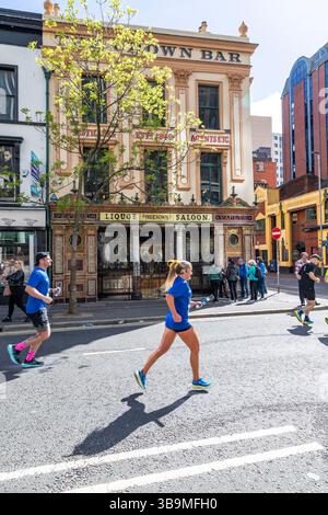 I corridori della maratona di Belfast corrono davanti al famoso Crown Bar di Belfast. Foto Stock