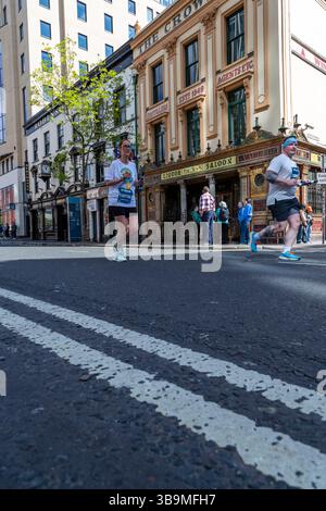 I corridori della maratona di Belfast corrono davanti al famoso Crown Bar di Belfast. Foto Stock