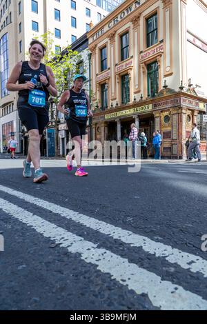 I corridori della maratona di Belfast corrono davanti al famoso Crown Bar di Belfast. Foto Stock