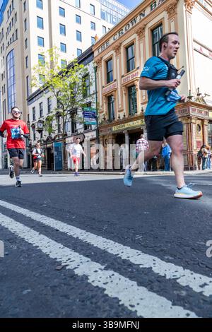 I corridori della maratona di Belfast corrono davanti al famoso Crown Bar di Belfast. Foto Stock