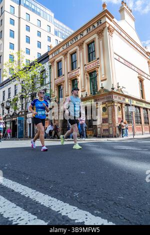 I corridori della maratona di Belfast corrono davanti al famoso Crown Bar di Belfast. Foto Stock