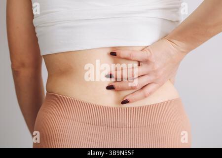 Donna con mal di schiena. Donna che tocca la vita. Sintomo di problema di salute. Disagio nella zona lombare. Tensione fisica o lesioni muscolari. Sollievo dal dolore. Foto Stock