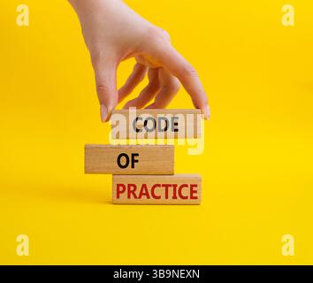 Simbolo del codice di pratica. Parola concettuale codice di pratica sui blocchi di legno. Mano d'affari. Bellissimo sfondo giallo. Business e codice di condotta Foto Stock