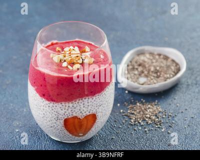 Idea per una sana prima colazione il giorno di San Valentino: Chia pudding con bacca rossa, purea di mandorle tritate sulla sommità e fragola a forma di cuore. Copia sp Foto Stock