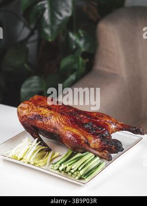 Anatra arrosto al forno - anatra intera al forno con cetriolo verde fresco e cipolla. Anatra alla pechinese sul tavolo del ristorante. L'anatra alla pechinese è un tradizionale cinese di Foto Stock