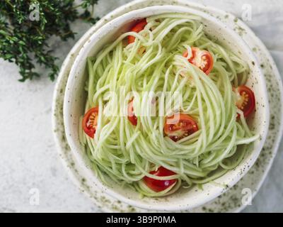 Insalata di tagliatelle di zucchine. Tagliatelle di verdure - zoodles verdi o spaghetti di zucchine con pomodori ciliegini in piatto. Cibo pulito, cibo vegetariano puro conc Foto Stock