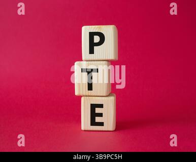 PTE - test Pearson del simbolo inglese. Cubi di legno con parola PTE. Bellissimo sfondo rosso. Business e PTE. Copia spazio. Foto Stock