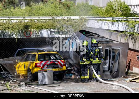 10 maggio 2025, Baviera, Erlangen: I vigili del fuoco stanno lavorando su un cockpit (modello) di aerei che si è schiantato in un vialetto di parcheggio sotterraneo come parte dell'esercitazione di controllo delle catastrofi "Löwenzahn". Nello scenario di esercitazione, un aereo cargo si è schiantato sopra il centro della città. Parti di un alto edificio sono state gravemente danneggiate. I piani superiori di un edificio di uffici adiacente sono in fiamme. E in un impianto chimico fittizio nelle vicinanze, la coda dell'aereo schiantata ha danneggiato diversi contenitori con merci pericolose. La cabina di pilotaggio dell'aereo si è schiantata su un'auto all'ingresso di un parcheggio sotterraneo Foto Stock