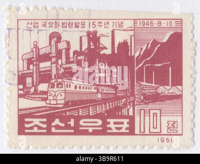 COREA DEL NORD, RPDC - 1961 luglio 11: Francobollo 10 chon rosso scuro-marrone raffigurante un poster della Juche Propaganda con treno elettrico, ascensore e fabbrica industriale. Lodando il quindicesimo anniversario della nazionalizzazione dell’industria Foto Stock