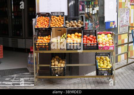 Stand di frutta di strada a Siviglia, Spagna, che espone arance fresche, mele, banane e pere in casse fuori da un piccolo negozio locale sul marciapiede della città. Foto Stock
