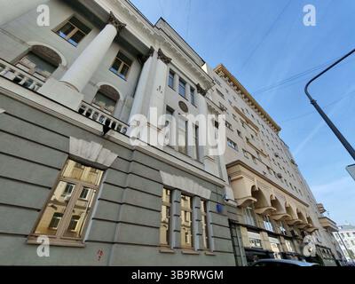 Un imponente edificio neoclassico con prominenti colonne bianche, intricati capitelli e lisce pareti grigie. L'immagine cattura la bellezza del classico Foto Stock
