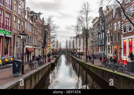 Paesi Bassi, Amsterdam, 13 febbraio 2025: Canale che si estende lungo il quartiere a luci rosse De Wallen di notte ad Amsterdam Paesi Bassi Foto Stock
