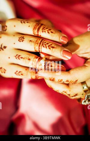 Un'immagine ravvicinata che mostra le mani di una donna adornate con motivi tradizionali mehndi (henné) e che indossa un anello di fidanzamento. Foto Stock