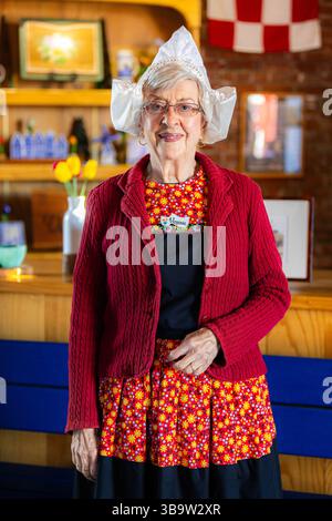 Olanda, mi, USA - 24-04-2025: Ritratto ravvicinato di una vecchia donna sorridente vestita con abiti tradizionali olandesi che mostrano orgoglio culturale e patrimonio culturale degli expres Foto Stock