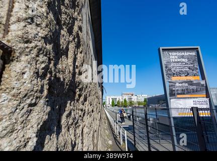 Pannello informativo presso il sito espositivo Topography of Terror con sezione del muro di Berlino conservata nel centro di Berlino, Germania. Foto Stock