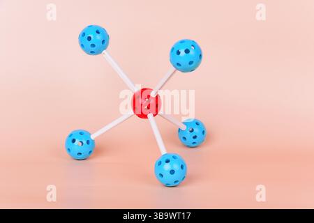 Modello molecolare con una sfera centrale rossa e sfere blu collegate da barre bianche, che rappresentano la struttura di una molecola Foto Stock