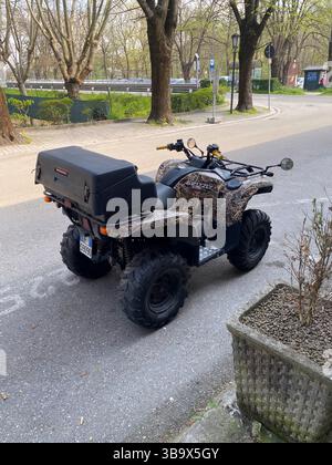 Cremona, Italia - 5 aprile 2025 Un quad incredibilmente mimetizzato si è posizionato all'aperto mostrando il suo design robusto e il suo pratico stoccaggio con la Sunligh Foto Stock