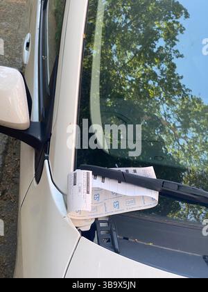 Cremona, Italia - 5 aprile 2025 la berlina argentata esposta con i biglietti di parcheggio rivela la presenza del veicolo parcheggiato a lato della strada in un cit Foto Stock