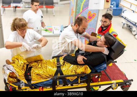 10 maggio 2025, Baviera, Erlangen: I dipendenti dell'ospedale universitario di Erlangen assistono una persona ferita (extra) nel reparto di triage del pronto soccorso nell'ambito dell'esercizio di controllo delle catastrofi "Löwenzahn". Nello scenario di esercitazione, un aereo cargo si è schiantato sopra il centro della città. Parti di un alto edificio sono state gravemente danneggiate. I piani superiori di un edificio di uffici adiacente sono in fiamme. E in un impianto chimico fittizio nelle vicinanze, la coda dell'aereo schiantata ha danneggiato diversi contenitori con merci pericolose. La cabina di pilotaggio dell'aereo si è schiantata su un'auto all'ingresso di un parcheggio sotterraneo Foto Stock