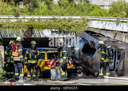 10 maggio 2025, Baviera, Erlangen: I vigili del fuoco stanno lavorando su un cockpit (modello) di aerei che si è schiantato in un vialetto di parcheggio sotterraneo come parte dell'esercitazione di controllo delle catastrofi "Löwenzahn". Nello scenario di esercitazione, un aereo cargo si è schiantato sopra il centro della città. Parti di un alto edificio sono state gravemente danneggiate. I piani superiori di un edificio di uffici adiacente sono in fiamme. E in un impianto chimico fittizio nelle vicinanze, la coda dell'aereo schiantata ha danneggiato diversi contenitori con merci pericolose. La cabina di pilotaggio dell'aereo si è schiantata su un'auto all'ingresso di un parcheggio sotterraneo Foto Stock