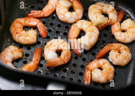 Gamberi grigliati nella friggitrice ad aria. Primo piano di un gustoso pasto a base di pesce. Succosi gamberi con spezie. Pranzo o cena salutari. Cucina in stile barbecue. Foto Stock