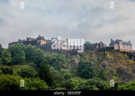 Castello di Edimburgo in Scozia sulla montagna Castle Rock circondato da lussureggianti alberi verdi in una serata estiva nuvolosa vista da nord Foto Stock