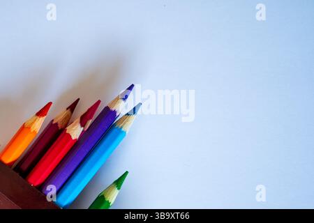 un gruppo di matite colorate si allunga su un foglio di carta bianco vuoto Foto Stock