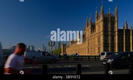 Le case del Parlamento dal ponte di Westminster che guarda a monte verso il Lambeth Bridge, con movimento sfocato persone e veicoli con cielo blu. Foto Stock