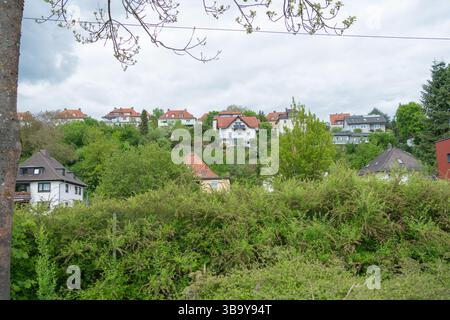 Pittoresca vista collinare della comunità che mette in risalto affascinanti case con tetti rossi annidate tra vegetazione lussureggiante, sotto un cielo parzialmente nuvoloso che crea un Foto Stock