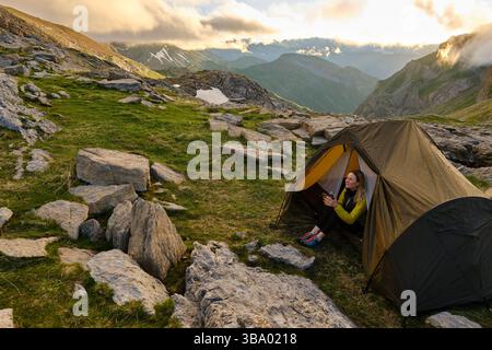 Donna in abiti caldi seduta con una tazza di caffè nella tenda del campo Foto Stock